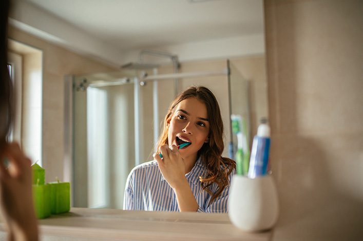 Woman brushing her teeth with fluoride toothpaste